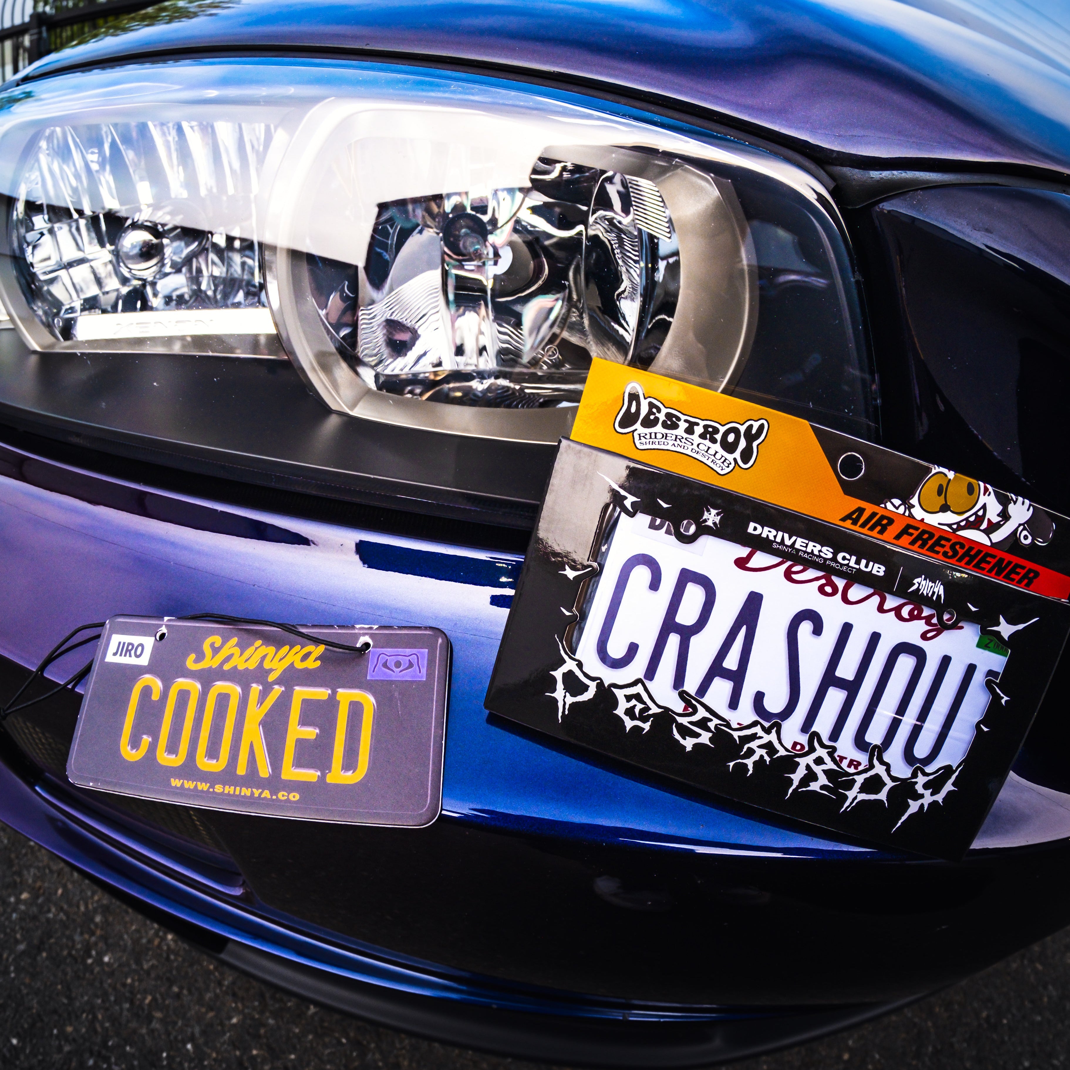 Close-up of a car's front headlight with personalized license plates.