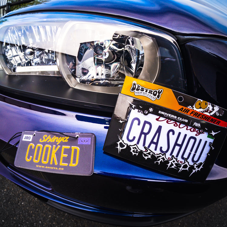 Close-up of a car's front headlight with personalized license plates.